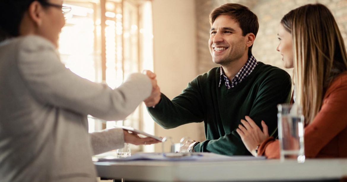 Casal Feliz Apertando As Maos Com Consultor Financeiro Durante Uma Reuniao No Escritorio O Foco Esta No Homem