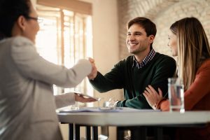 Casal Feliz Apertando As Maos Com Consultor Financeiro Durante Uma Reuniao No Escritorio O Foco Esta No Homem