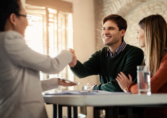 Casal Feliz Apertando As Maos Com Consultor Financeiro Durante Uma Reuniao No Escritorio O Foco Esta No Homem